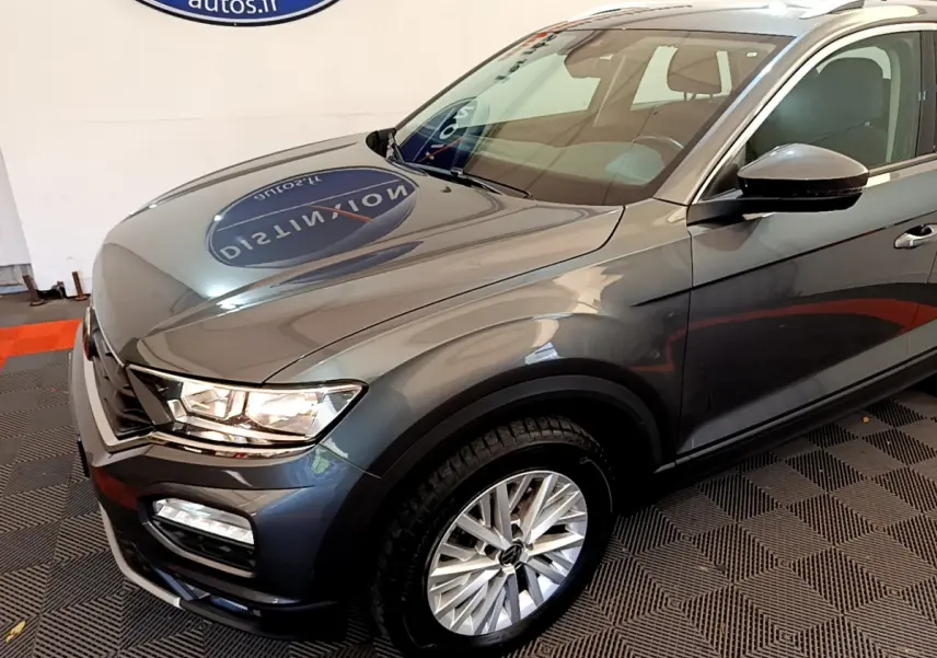 Vue 3/4 avant droit d'un Volkswagen T-Roc gris foncé avec jantes alliage et phares LED visibles.