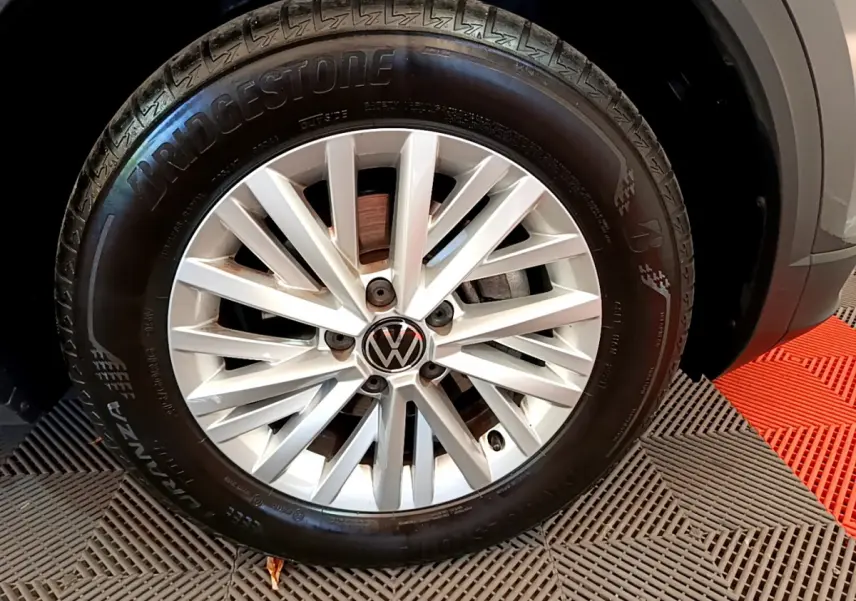 Gros plan sur la roue avant droite du Volkswagen T-Roc gris foncé avec jante alliage et pneu Bridgestone.