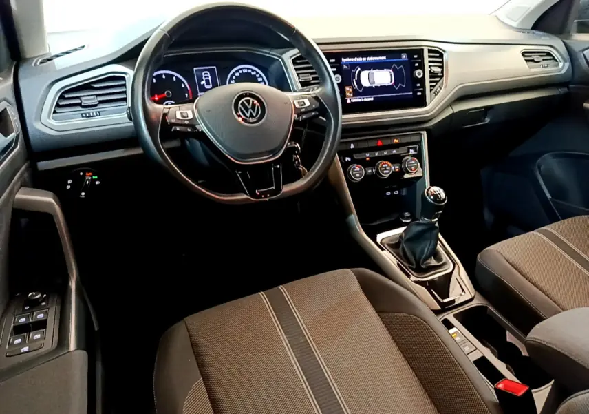 Intérieur du Volkswagen T-Roc 1.0 TSI 2021, vue depuis le siège conducteur, tableau de bord et console centrale avec écran tactile.