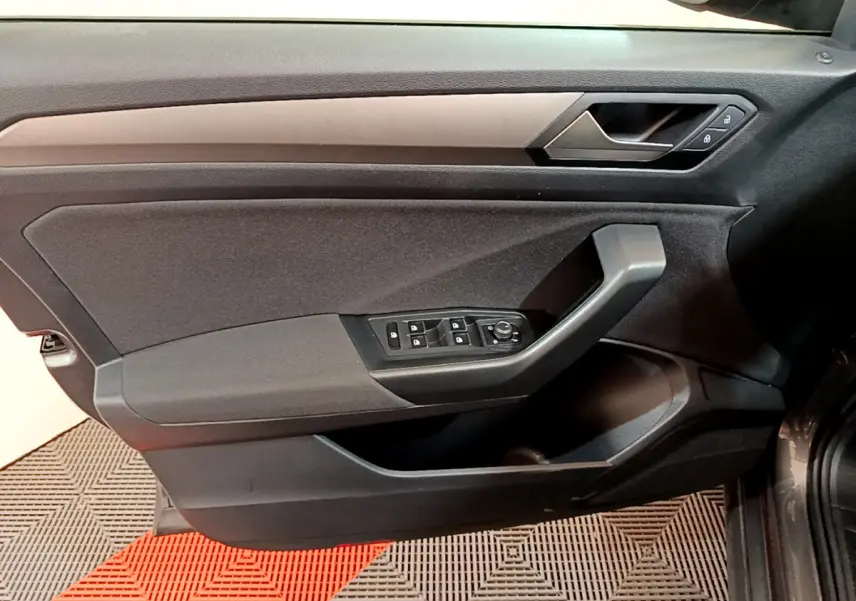 Vue intérieure du panneau de porte côté conducteur du Volkswagen T-Roc gris foncé, avec commandes électriques et poignée angulaire.