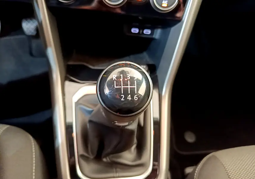 Le levier de vitesses manuel noir du Volkswagen T-Roc 1.0 TSI 110 Lounge Business vu de dessus, entouré de garnitures grises.