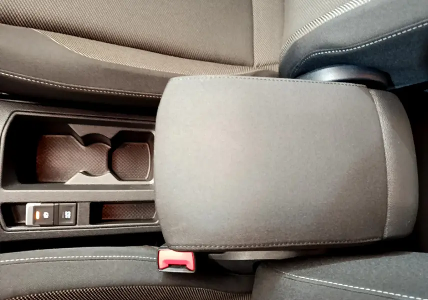 Gros plan sur l'accoudoir central et porte-gobelets du Volkswagen T-Roc gris foncé, intérieur tissu noir.