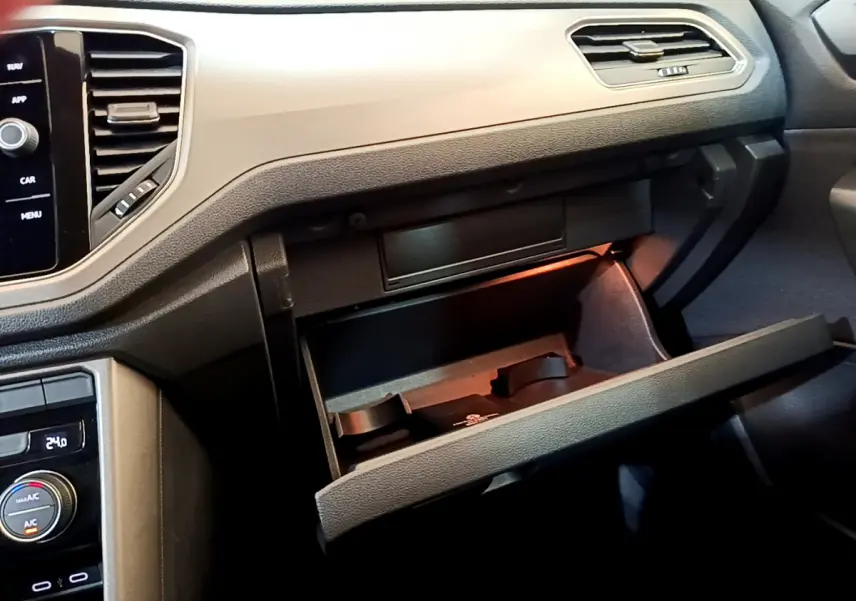 Intérieur du Volkswagen T-Roc 2021, vue du tableau de bord côté passager avec boîte à gants ouverte et éclairage intérieur.