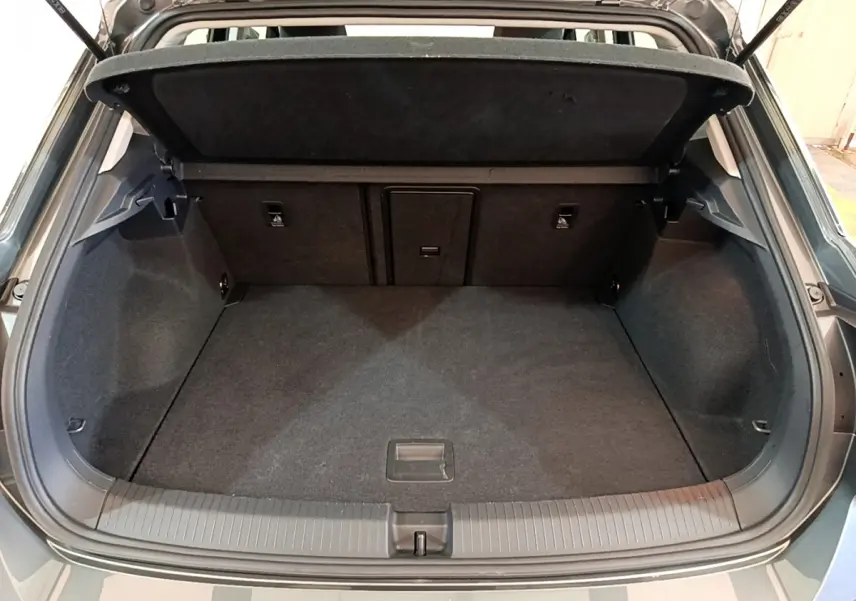 Coffre ouvert d'un Volkswagen T-Roc gris foncé, vue arrière montrant l'espace de chargement et la tablette amovible.