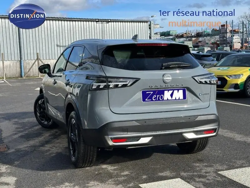 Vue 3/4 arrière droite du Nissan Qashqai Hybrid e-POWER 2025 en gris Argile, avec feux arrière LED et logo distinctif.