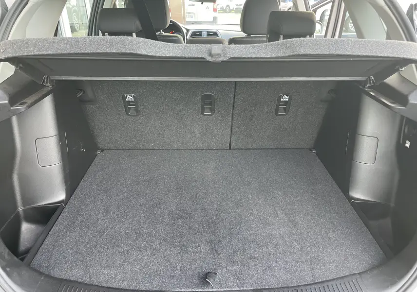 Coffre ouvert d'un Suzuki SX4 S-CROSS gris, montrant l'espace de chargement et la banquette arrière rabattable.