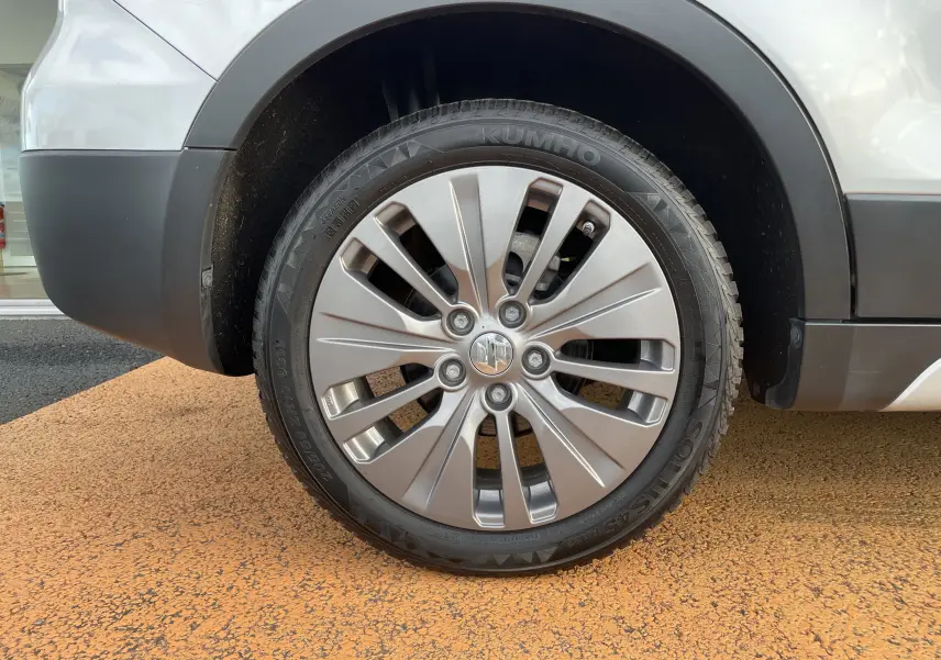 Gros plan sur la roue avant gauche grise d'un Suzuki SX4 S-CROSS 2016 avec jante en alliage et logo Suzuki au centre.