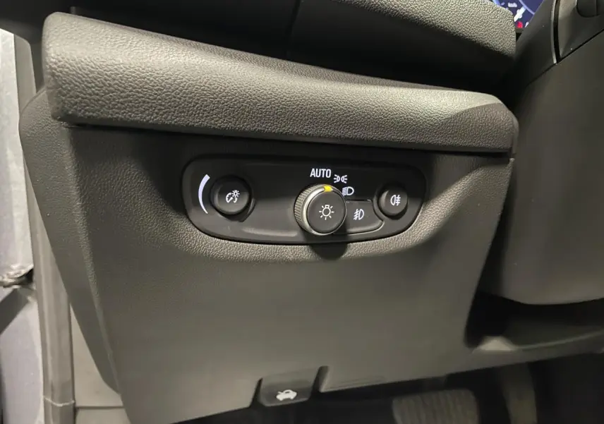 Gros plan sur les commandes d'éclairage noires sous le tableau de bord d'une Opel Insignia Grand Sport gris clair.