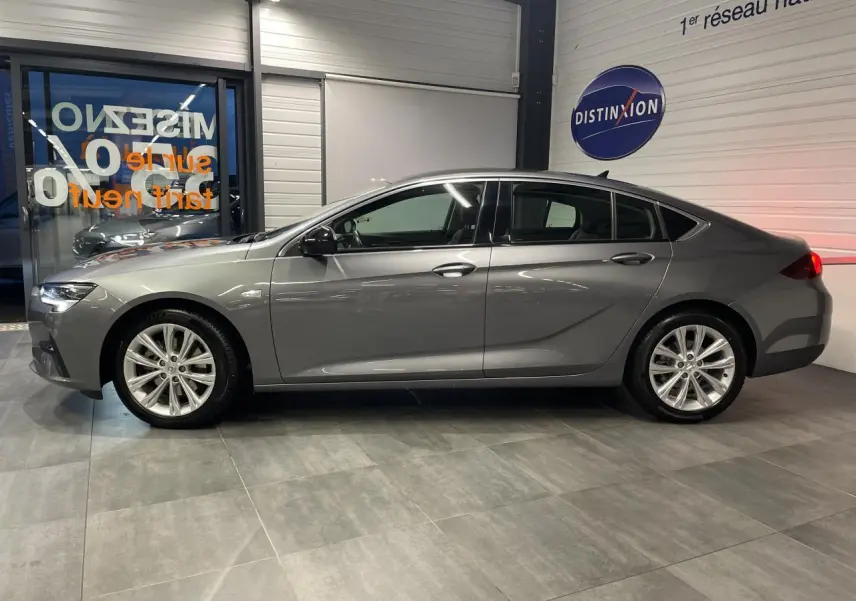 Opel Insignia Grand Sport gris clair vue de profil côté gauche dans un showroom avec jantes alliage 17 pouces.