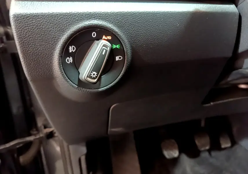 Gros plan sur le bouton de commande des phares à gauche du volant dans l'habitacle du Volkswagen T-Roc gris foncé 2021.