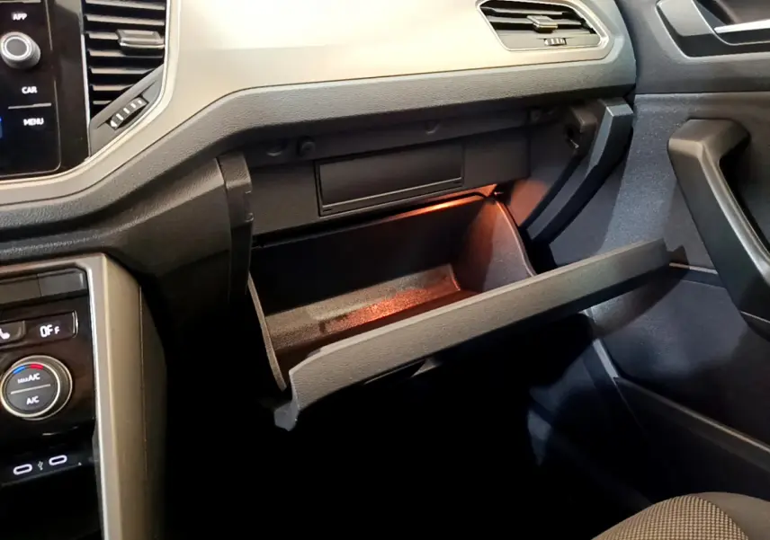 Gros plan de la boîte à gants ouverte côté passager dans l'habitacle sombre du Volkswagen T-Roc 2021.