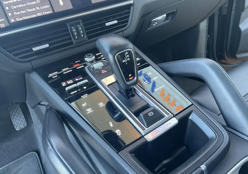 Vue rapprochée de la console centrale noire du Porsche Cayenne Coupé E-Hybrid 2021 avec levier de vitesses automatique et commandes tactiles.
