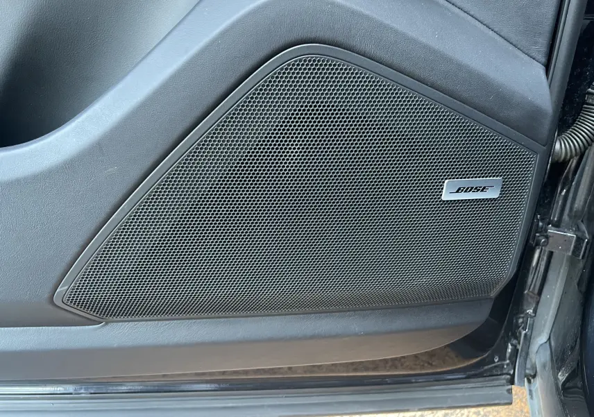 Gros plan sur l'enceinte Bose intégrée à la porte côté gauche d'un Porsche Cayenne Coupé E-Hybrid noir.