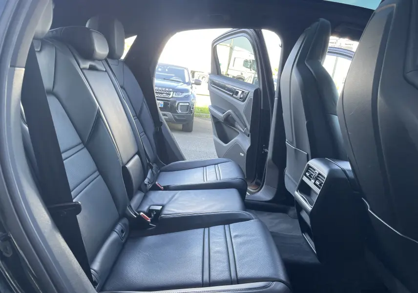Vue intérieure côté droit des sièges arrière en cuir noir du Porsche Cayenne Coupé E-Hybrid 2021 avec porte arrière ouverte.