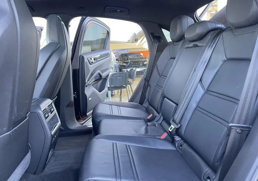 Vue intérieure côté droit des sièges arrière en cuir noir du Porsche Cayenne Coupé E-Hybrid 2021 avec porte ouverte.