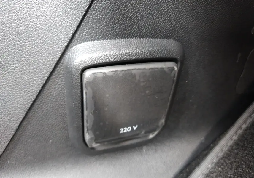 Prise 220 V noire intégrée dans le panneau intérieur gris foncé du Peugeot Rifter 1.5 BlueHDI 130ch GT 2022.