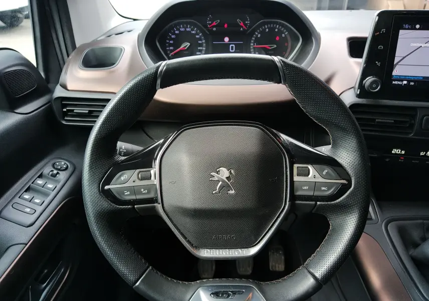 Vue rapprochée du volant noir perforé avec logo Peugeot et tableau de bord digital du Rifter 2022.
