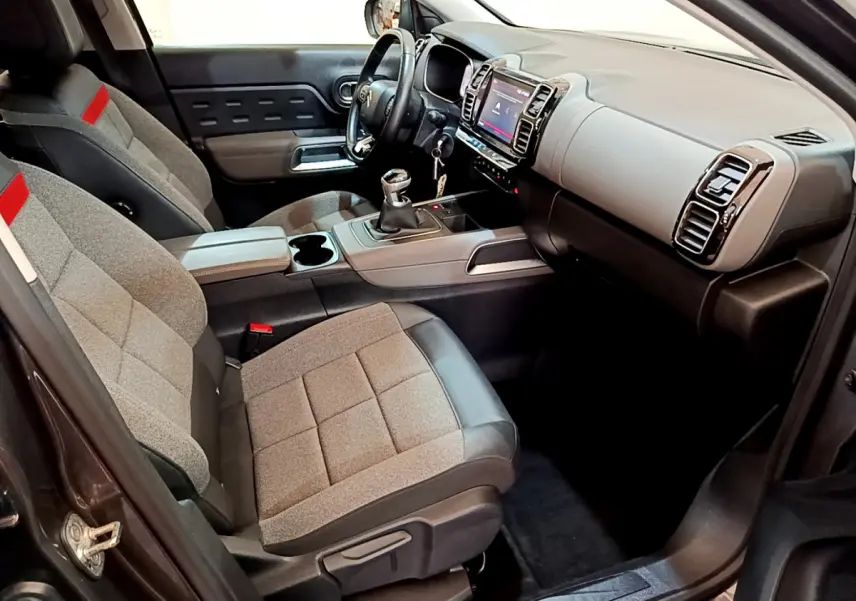 Intérieur avant droit du Citroën C5 Aircross gris foncé, sièges tissu gris et cuir noir, console centrale avec boîte manuelle.