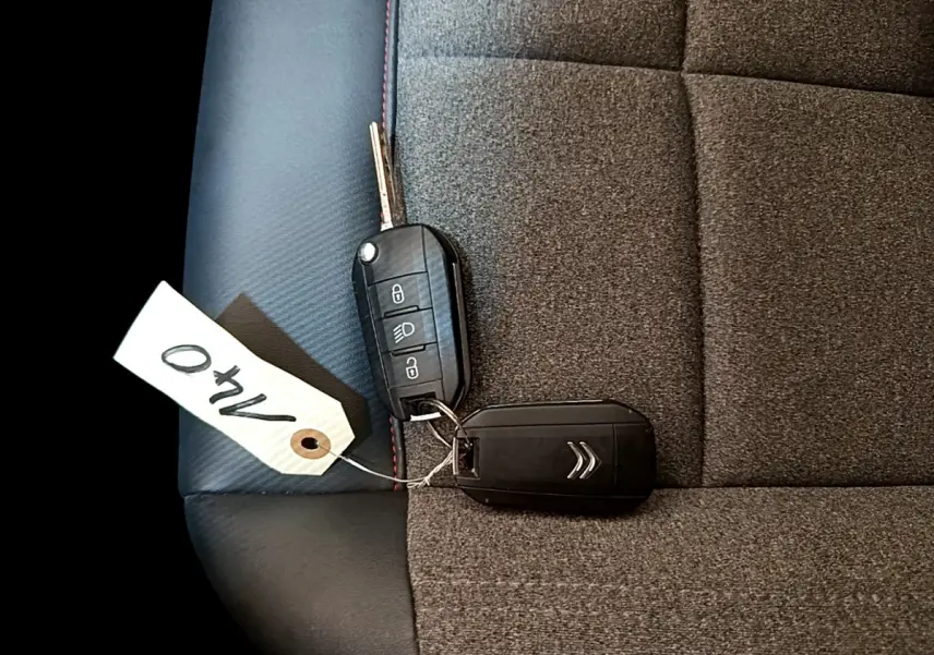 Clé de voiture Citroën posée sur siège tissu gris foncé avec surpiqûres rouges, intérieur du C5 Aircross 2020.