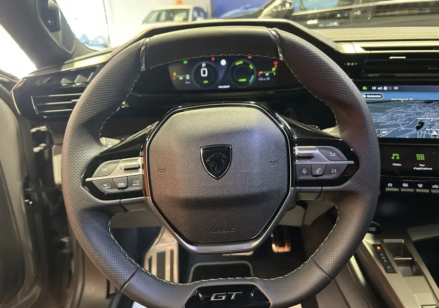 Vue rapprochée du volant GT en cuir perforé avec instrumentation numérique et écran GPS du Peugeot 308 gris Selenium.