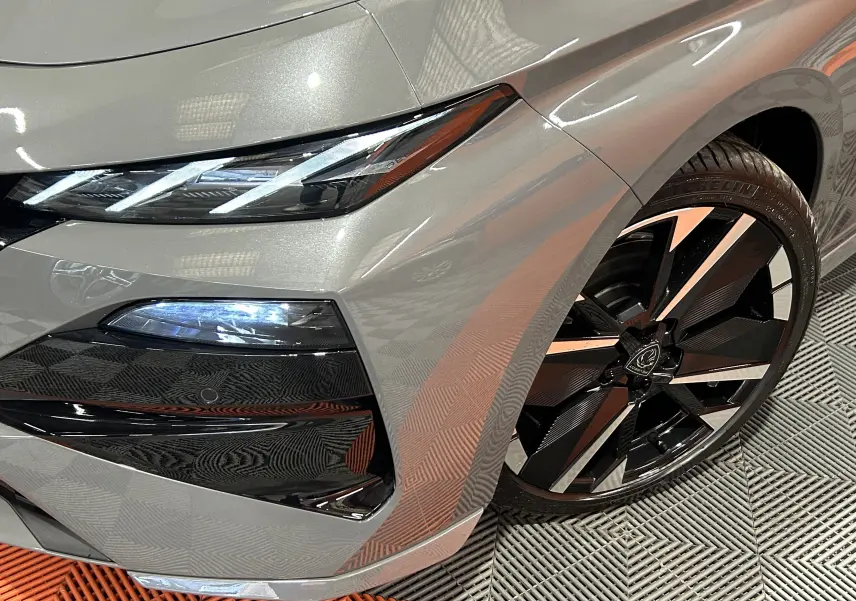 Gros plan sur l’avant droit gris Selenium du Peugeot 308 III Ph.2 HYBRID 145 GT avec optique LED et jante noire et argent.