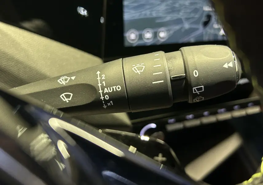 Gros plan sur la commande des essuie-glaces dans l’habitacle de la Peugeot 308 gris Selenium, avec écran tactile en arrière-plan.
