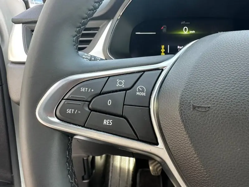 Gros plan sur les commandes multifonctions noires à gauche du volant du Renault Captur blanc nacré 2025.