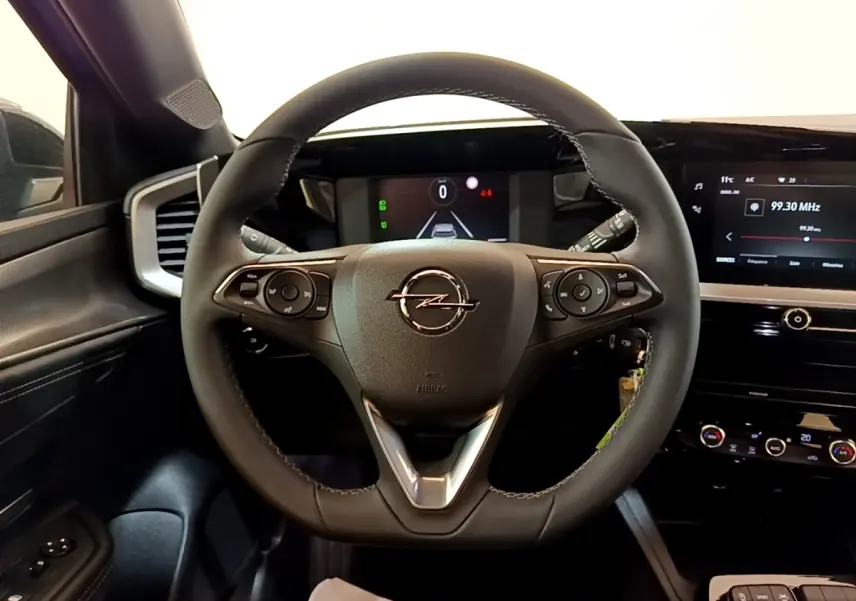Vue intérieure centrée sur le volant cuir noir de l'Opel Mokka 2024 avec tableau de bord digital et écran tactile.