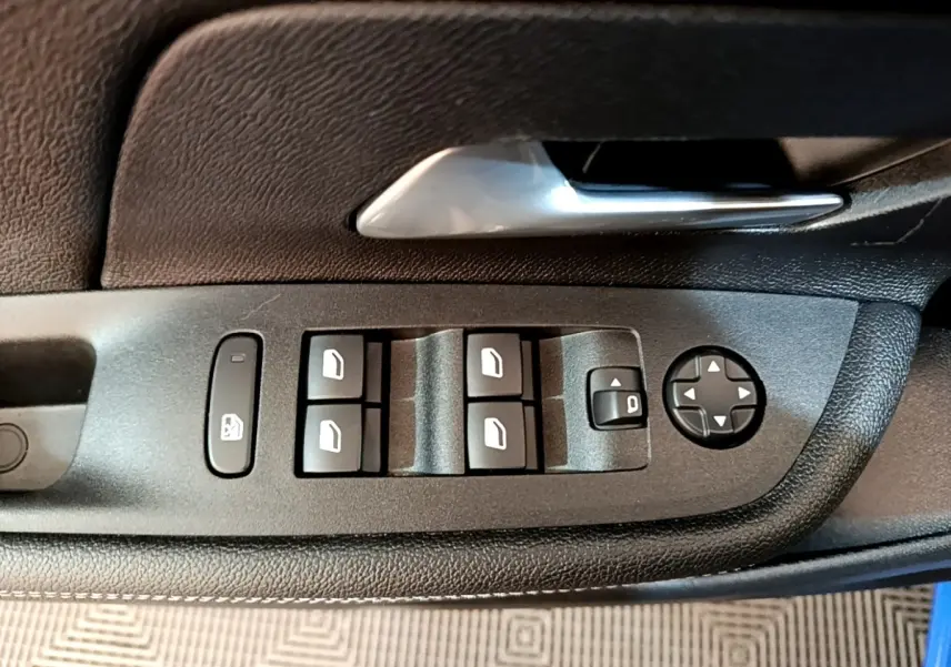 Gros plan sur les commandes des vitres et rétroviseurs côté conducteur de l’Opel Mokka bleu 2024.