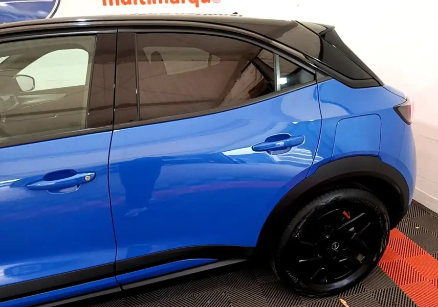 Vue latérale droite d'un Opel Mokka bleu 2024 avec toit noir et jantes noires brillantes.