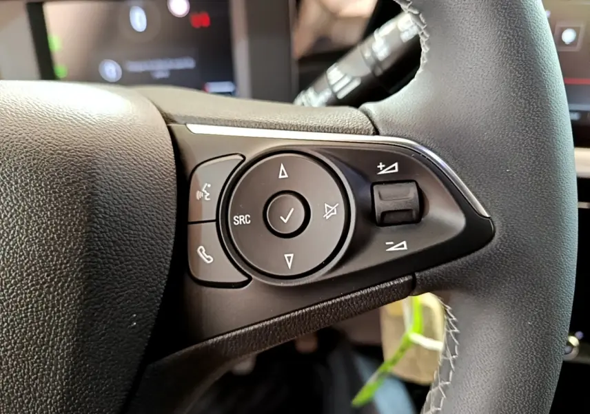 Gros plan sur les commandes multifonctions du volant en cuir noir de l'Opel Mokka 2024, version essence.
