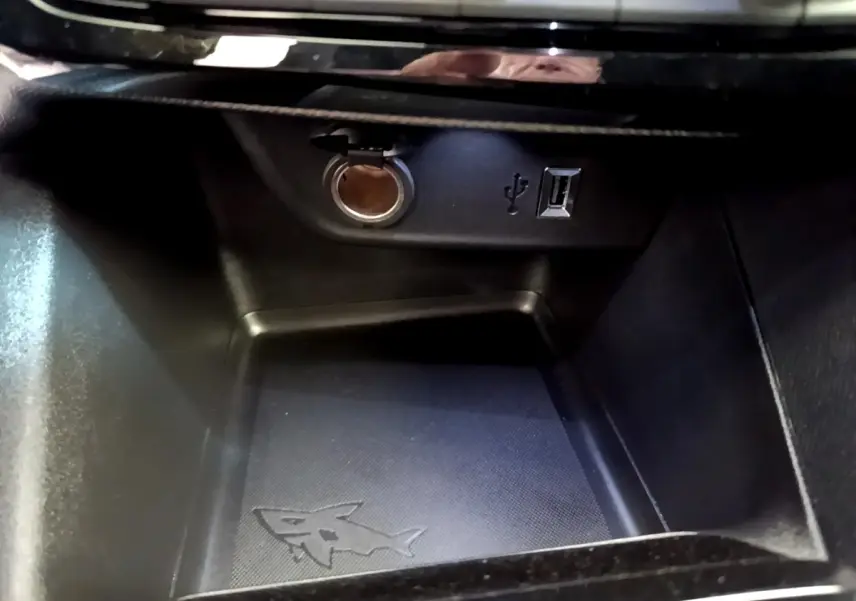 Gros plan sur la prise 12V et port USB dans le compartiment de rangement intérieur de l’Opel Mokka bleu.