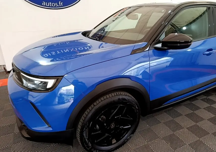 Vue 3/4 avant gauche d’un Opel Mokka bleu 2024 avec jantes noires et rétroviseurs noirs brillants.