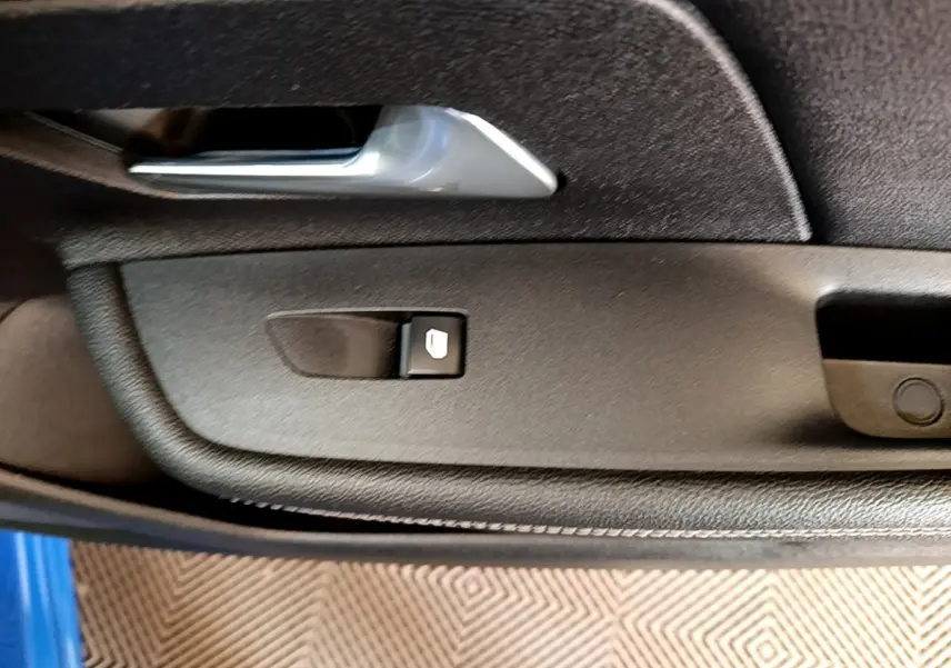 Détail de la commande de lève-vitre sur la porte côté conducteur d’un Opel Mokka bleu 2024.