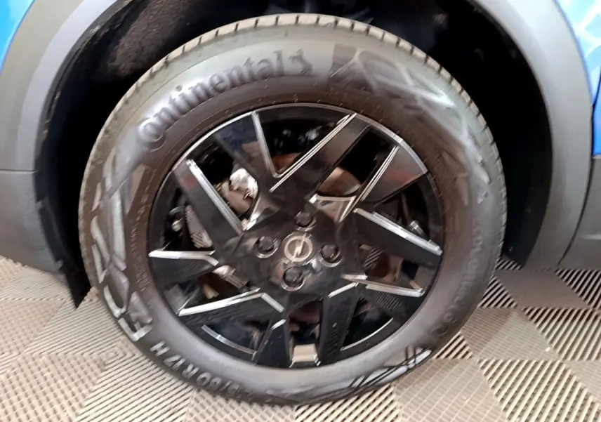 Gros plan sur la roue avant droite noire avec jante en alliage du SUV Opel Mokka bleu 2024.