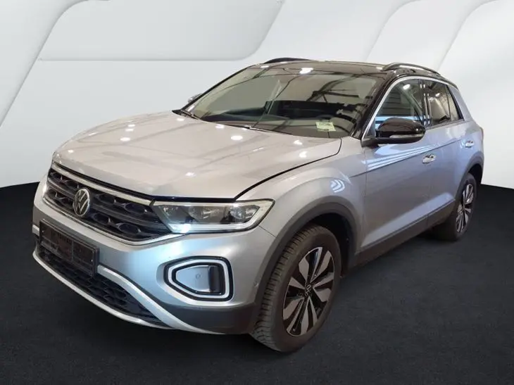 Volkswagen T-Roc gris clair en 3/4 avant droit, avec toit noir et feux LED allumés.
