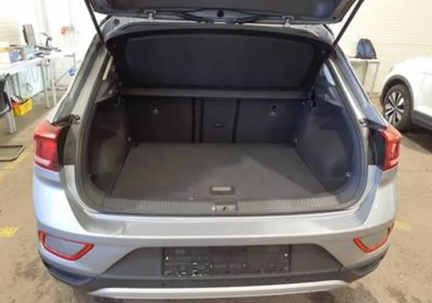 Vue arrière du coffre ouvert d'un Volkswagen T-Roc gris clair 2025, montrant l'espace de chargement vide.