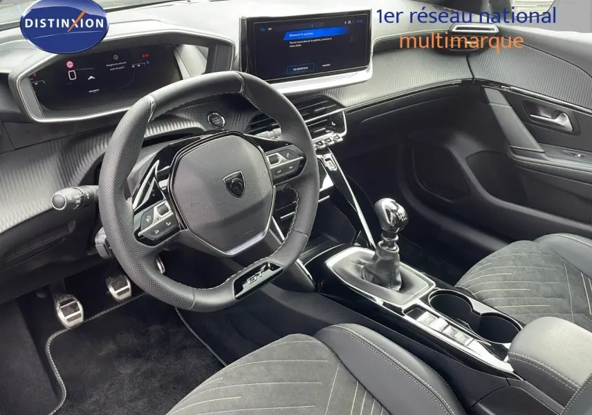 Intérieur Peugeot 208 GT 2025 vu côté conducteur, volant GT, sellerie noire et levier de vitesse manuel.