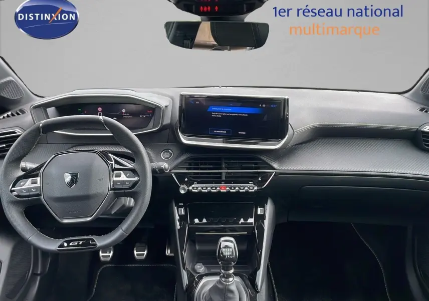 Vue intérieure frontale du tableau de bord de la Peugeot 208 GT 2025 avec volant compact et écran tactile central.