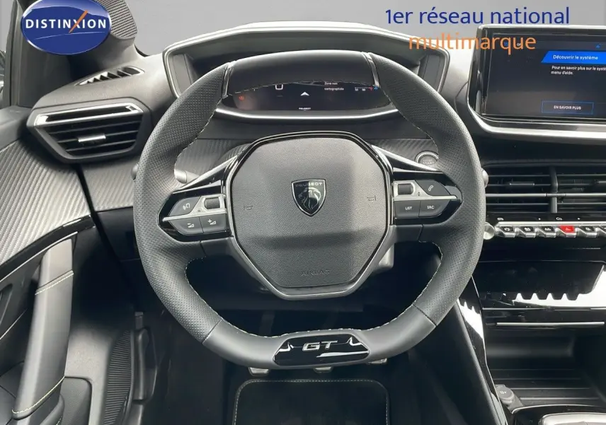 Vue intérieure centrée sur le volant GT de la Peugeot 208 gris selenium avec tableau de bord numérique et écran tactile.