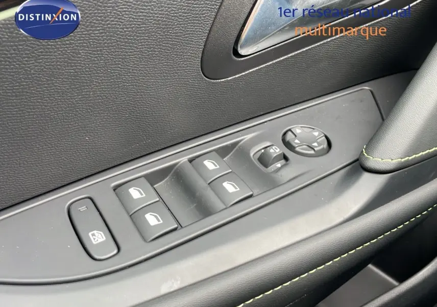 Gros plan sur les commandes des vitres électriques et rétroviseurs côté gauche intérieur d'une Peugeot 208 gris sélénium toit noir.