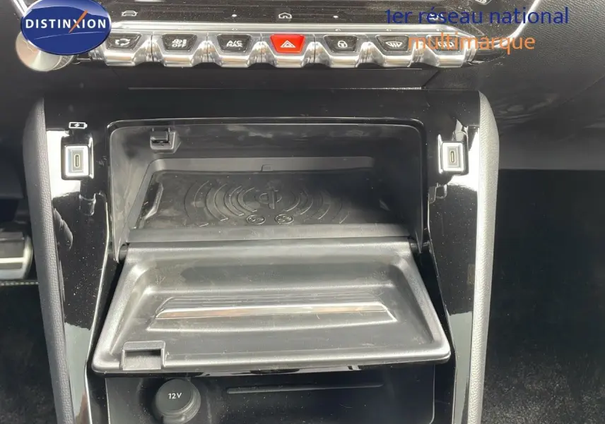 Console centrale de Peugeot 208 GT 2025 en gris, montrant la zone de recharge sans fil et les commandes de climatisation.