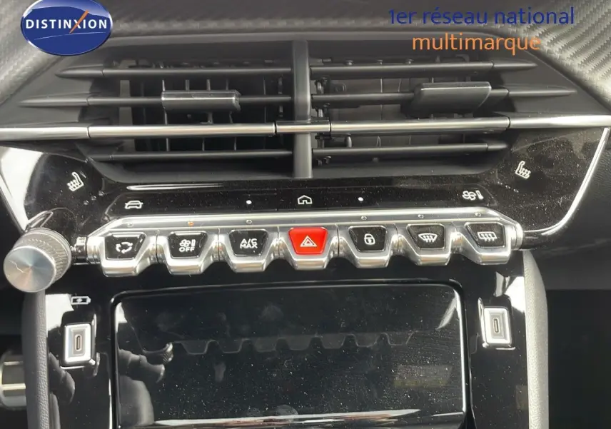 Gros plan sur la console centrale de la Peugeot 208 1.2 PureTech 2025, avec boutons de commande et aérateurs noirs brillants.