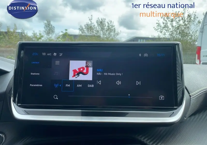 Écran tactile central de la Peugeot 208 2025 affichant la radio NRJ avec interface moderne et tableau de bord noir.