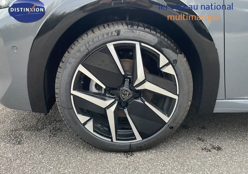 Gros plan sur la roue avant gauche de la Peugeot 208 gris selenium avec jante alliage bicolore moderne.