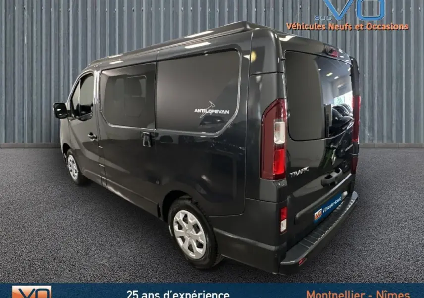 Vue 3/4 arrière droite du Renault Trafic Fourgon gris avec vitres surteintées et logo Antilopevan sur la porte latérale.