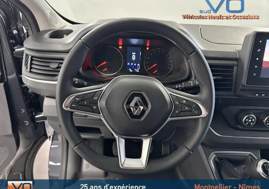Vue intérieure centrée sur le volant noir du Renault Trafic Fourgon gris avec tableau de bord et commandes visibles