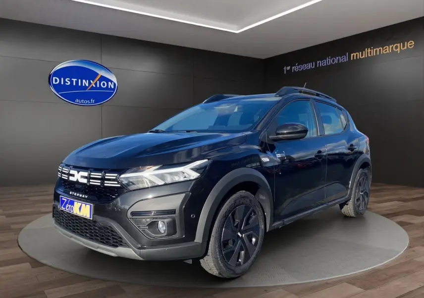 Dacia Sandero Stepway noir en 3/4 avant droit, avec barres de toit et jantes noires distinctives.