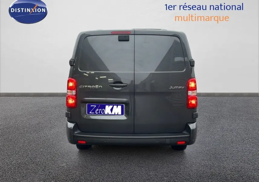 Vue arrière d'un Citroën Jumpy cabine approfondie gris titane avec feux allumés sur sol bitumé.