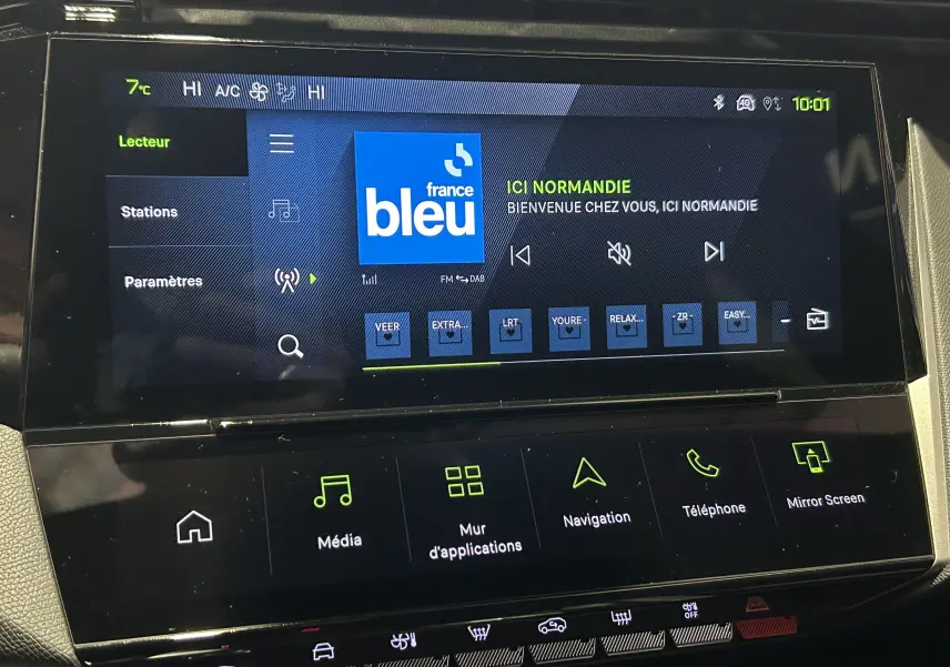 Écran tactile central du tableau de bord de la Peugeot 308 blanc Okenite, affichant l’interface radio France Bleu.